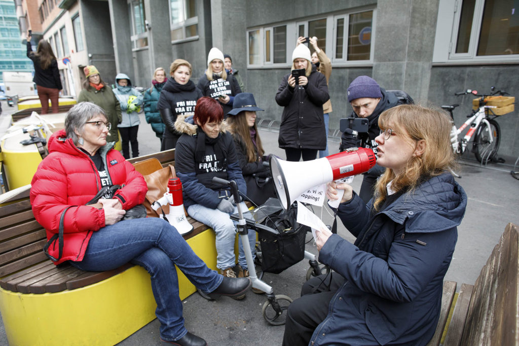 Martine Eliasson med megafon sammen med andre frammøtte foran departementet.
