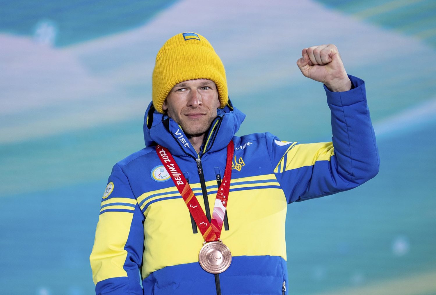 Grygorij Vovtsjynski med medalje rundt halsen og knyttneven hevet i en seiersgest. han er kledd i ukrainske gule og blå farger.