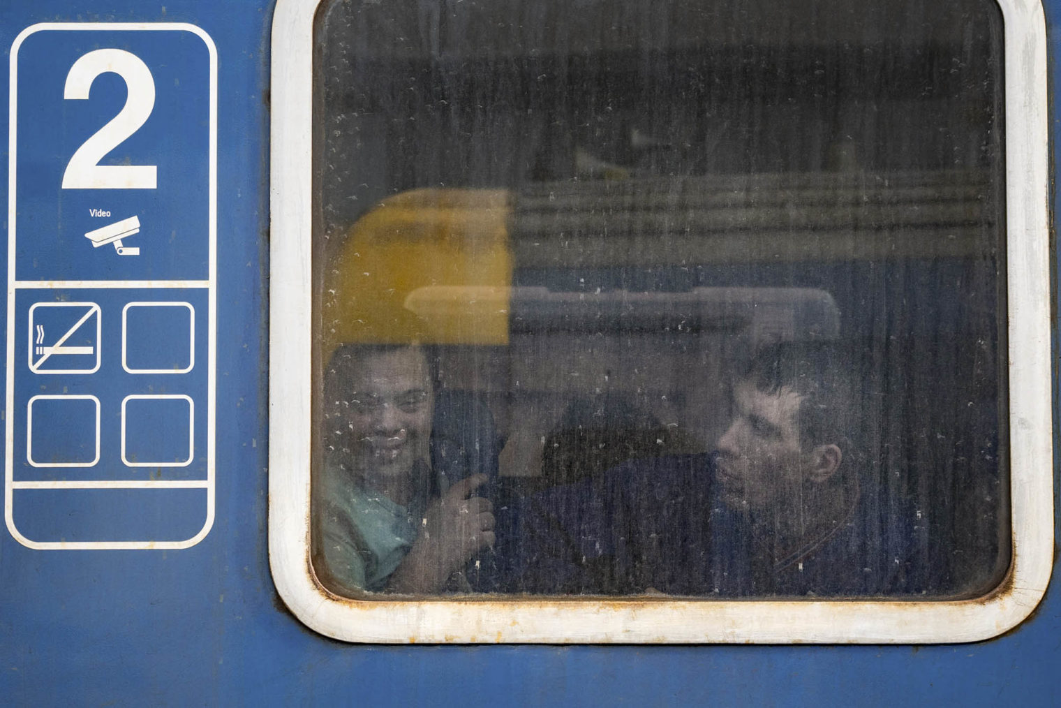 To barn eller ungdommer ser ut gjennom et togvindu.