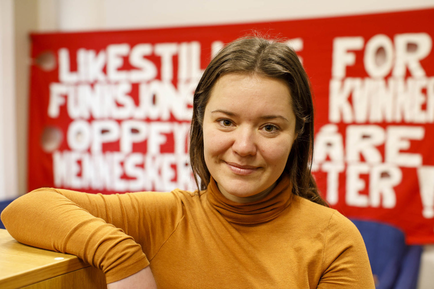 Guro Helen Sørdalen med en plakat med paroler i bakgrunnen.