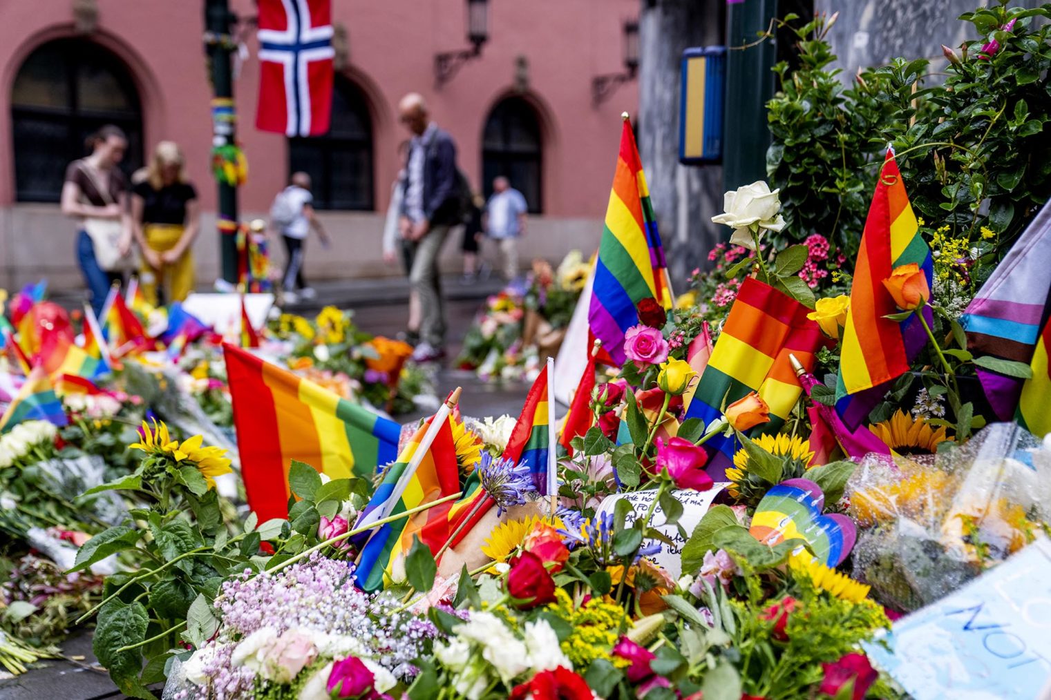Bilde av store mengder blomster og regnbueflagg på gaten utenfor puben.