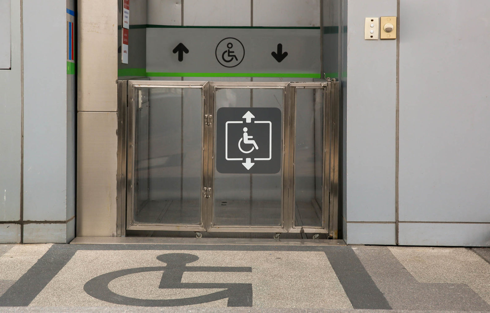 Bilde av heis med rullestol-piktobram både på gulvet foran og på heisdøren.