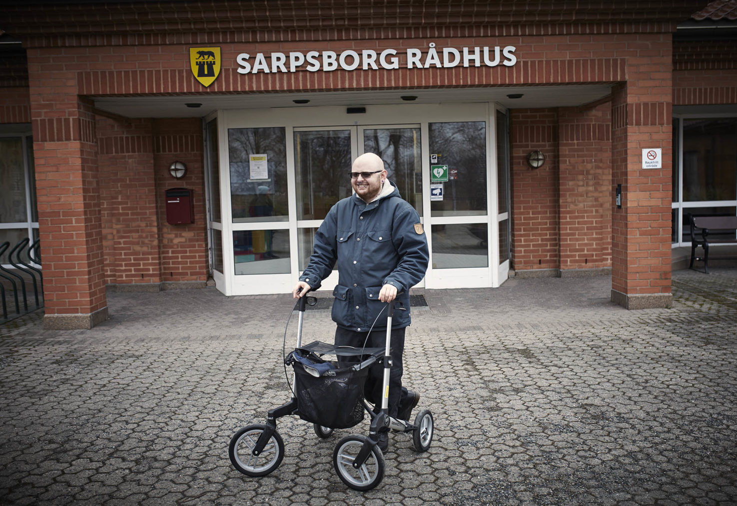 Axel med rullatoren foran inngangen til Sarpsborg rådhus.