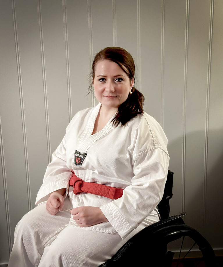 Merete poserer i taekwondodrakt, sittende i rullestol.
