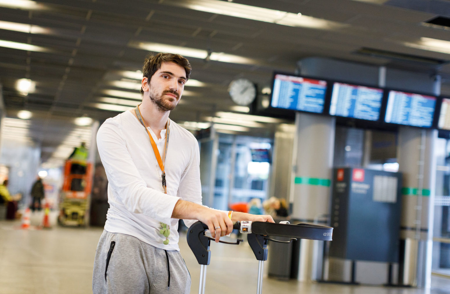 Amir Hashani fotografert med rullator inne på en bussterminal. I Bagrunnen skjermer med avtangstider.