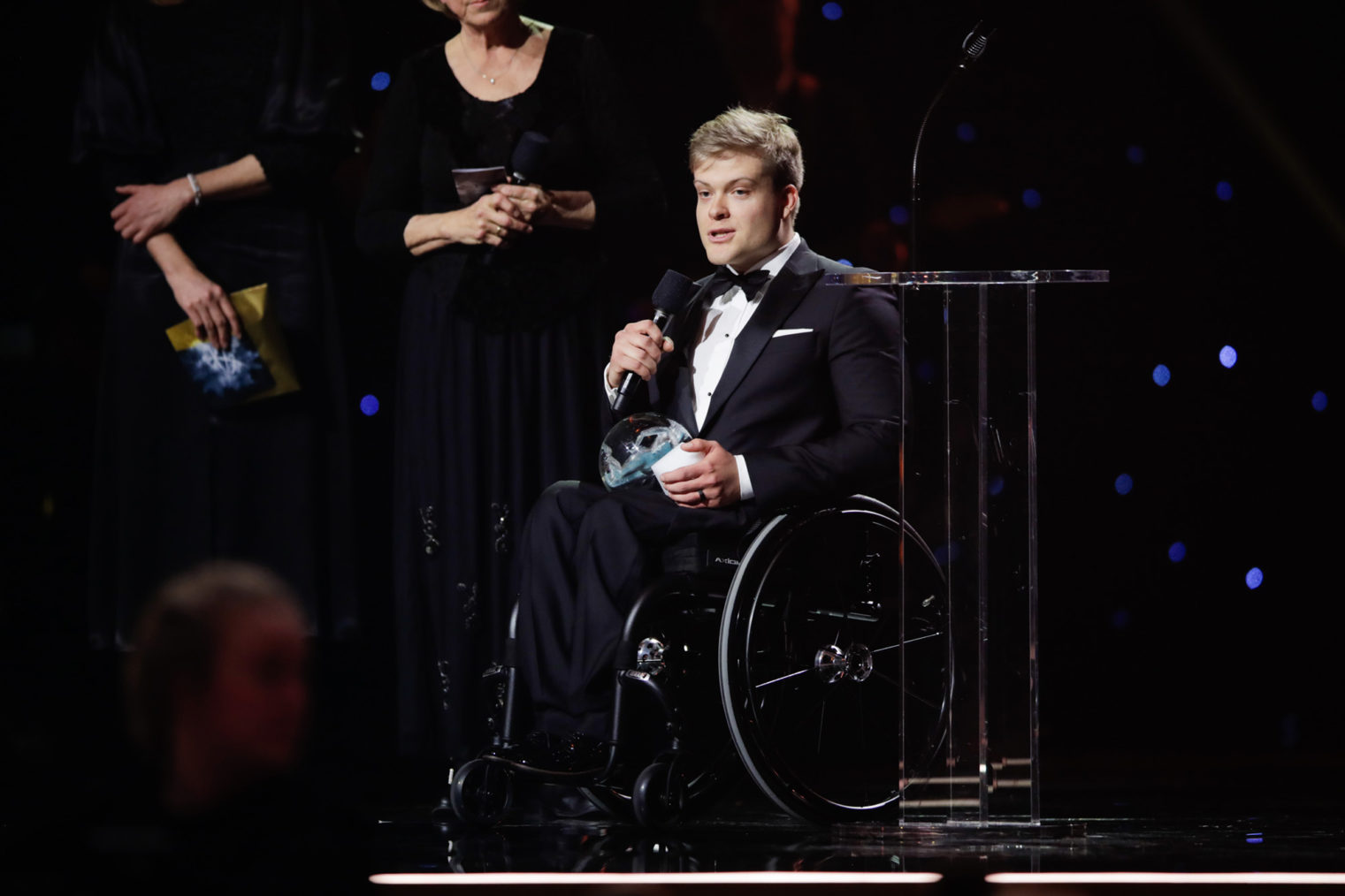 Jesper Saltvik Pedersen på podiet, i rullestol, holder takketale.