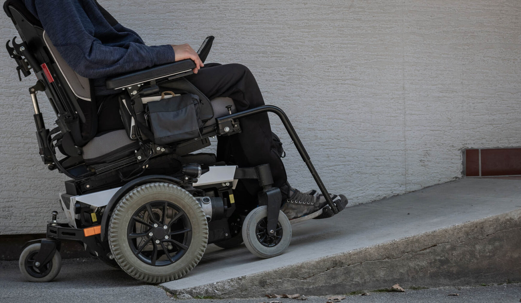 Illustrasjonsfoto av en person i elektrisk rullestol på vei opp en rampe.