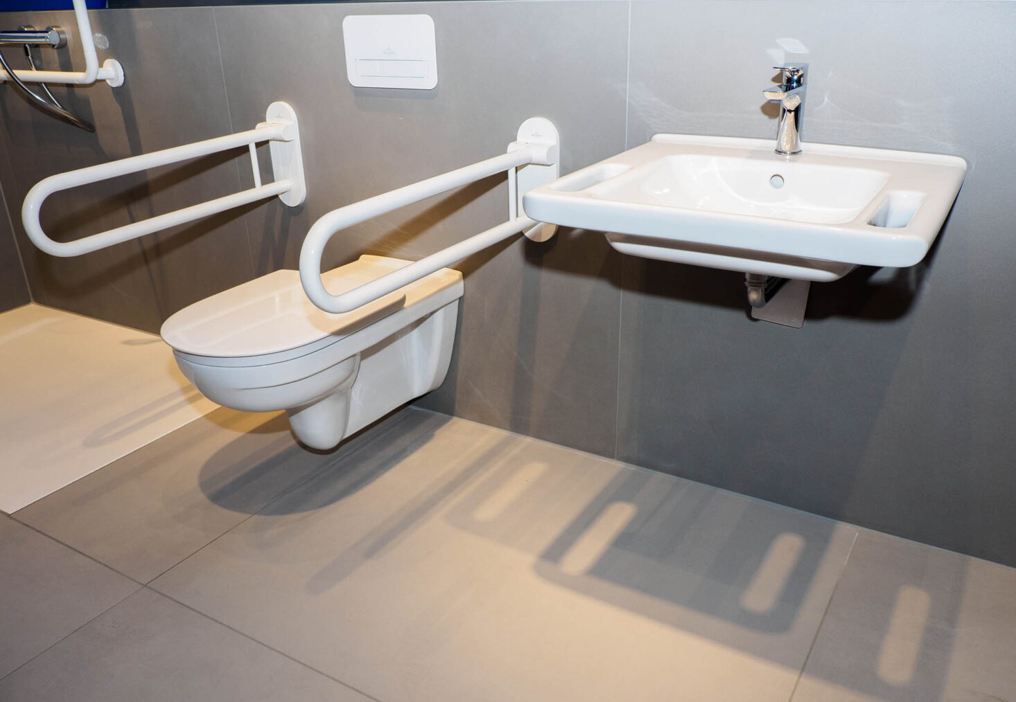 Bilde av baderomsinnredning på messestand, med toalett med håndtak.