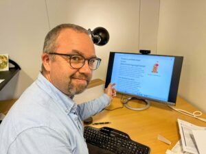 Kristian Lian sitter ved skrivebordet og peker på dataskjermen der Diskrimineringsnemnda skriver om avgjørelsen om pakkeboksene.