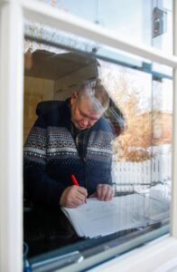 Thorvald Steen sitter ved vinduet og skriver. Bildet er tatt utenfra.