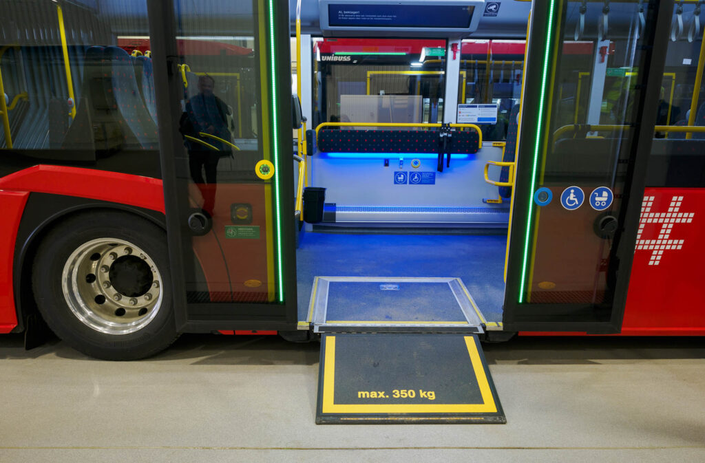 Bilde av bussen med rampen ute og døren åpen inn mot rullestolplassen.