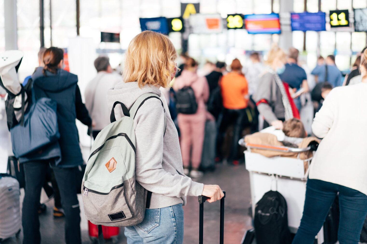 Kvinne fotografert bakfra som skal sjekke inn på en flyplass.