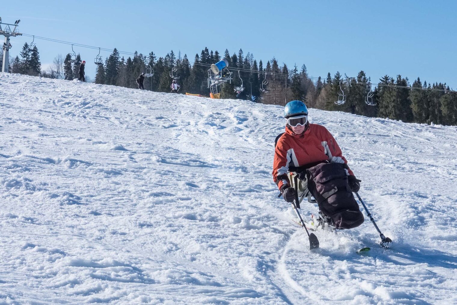 Mann kjører sitski i en slalåmbakke.