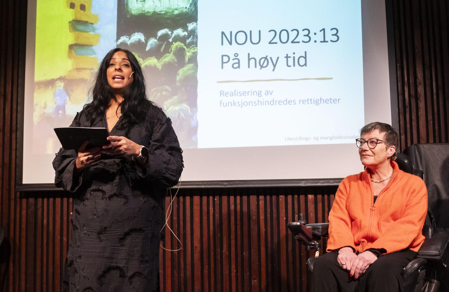 Jaffery og Brandvik på scenen. På skjermen bak e forsiden på utredningen «På høy tid».