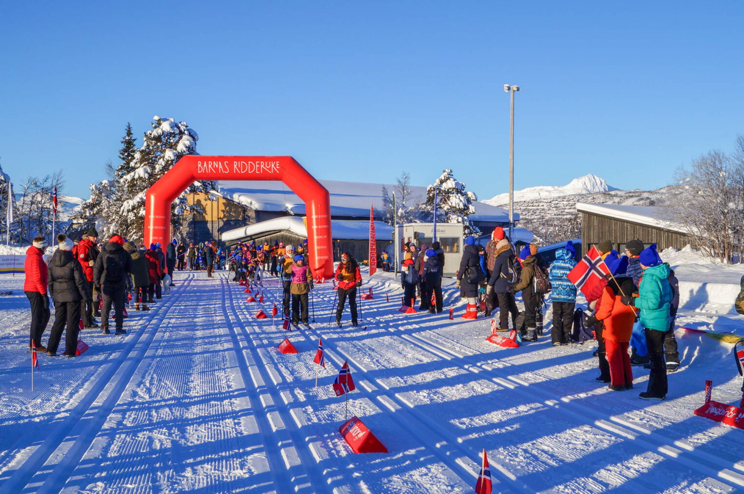 Oversiktsbilde av startomårdet med skiløpyer. Strålende sol.
