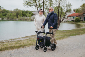 Mann med rullator går ved siden av kvinne på gangvei