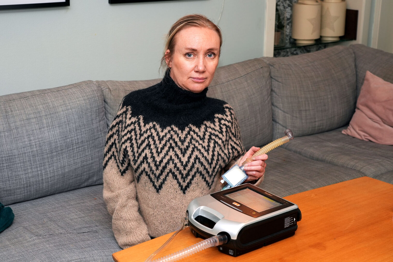 Guro Skjetne sitter i sofa og viser frem pustemaskin