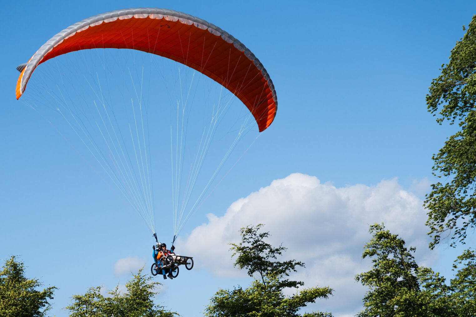 Tove Linnea Brandvik med ledsager i paraglider over grantopper