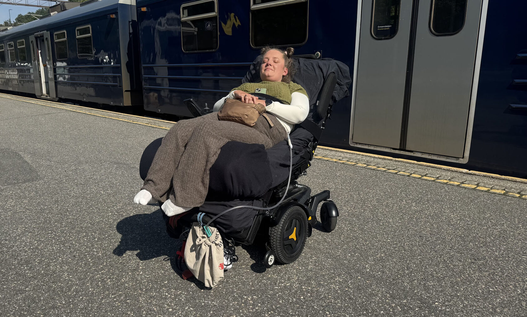 Marianne Knudsen i el-rullestol på togperrong, tog i bakgrunnen