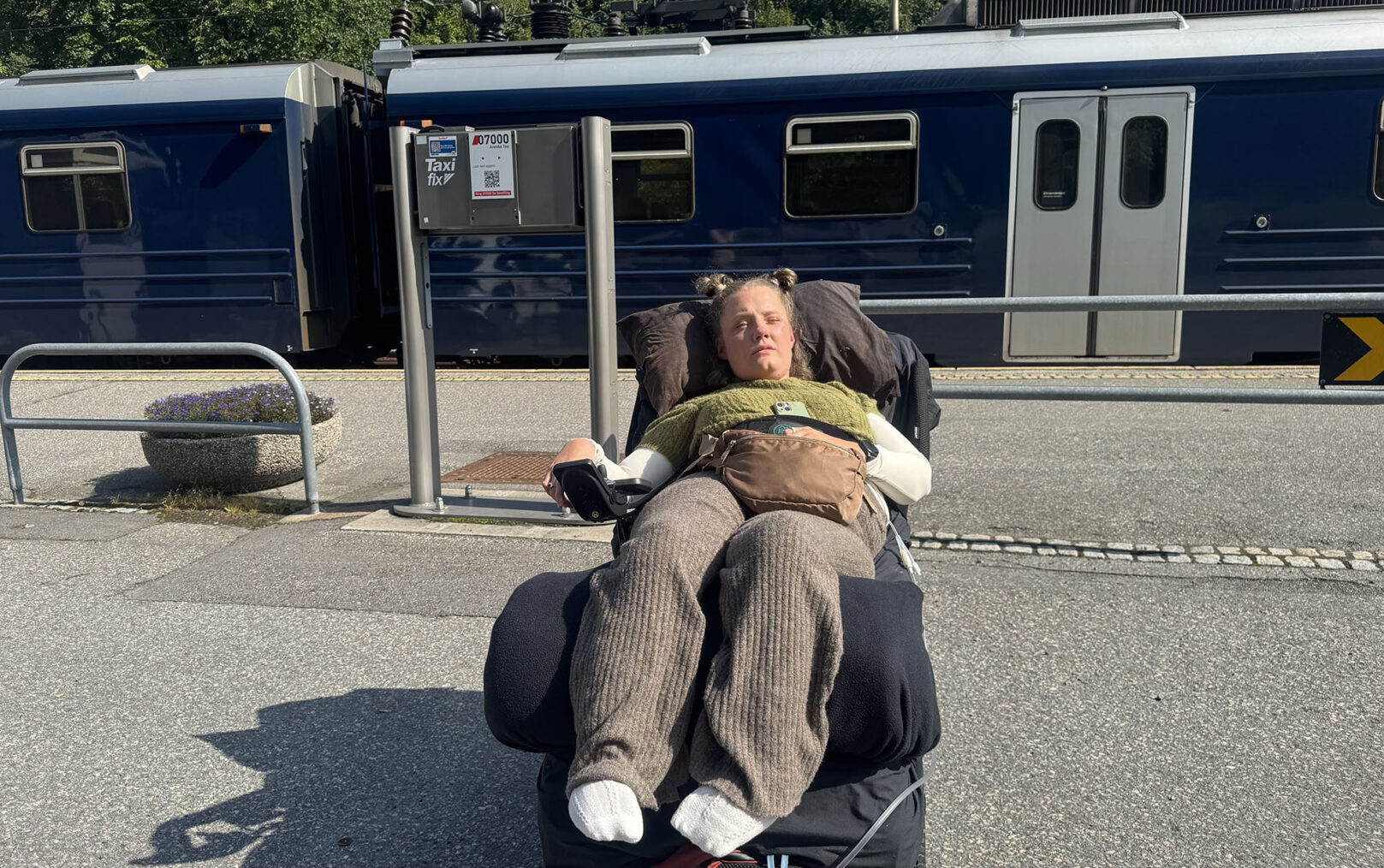 Marianne Knudsen i el-rullestol på perrong med tog i bakgrunnen