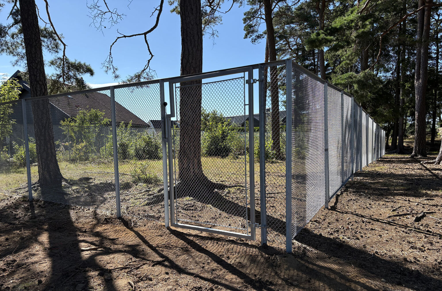 Høye nettinggjerder i skolegård med trær