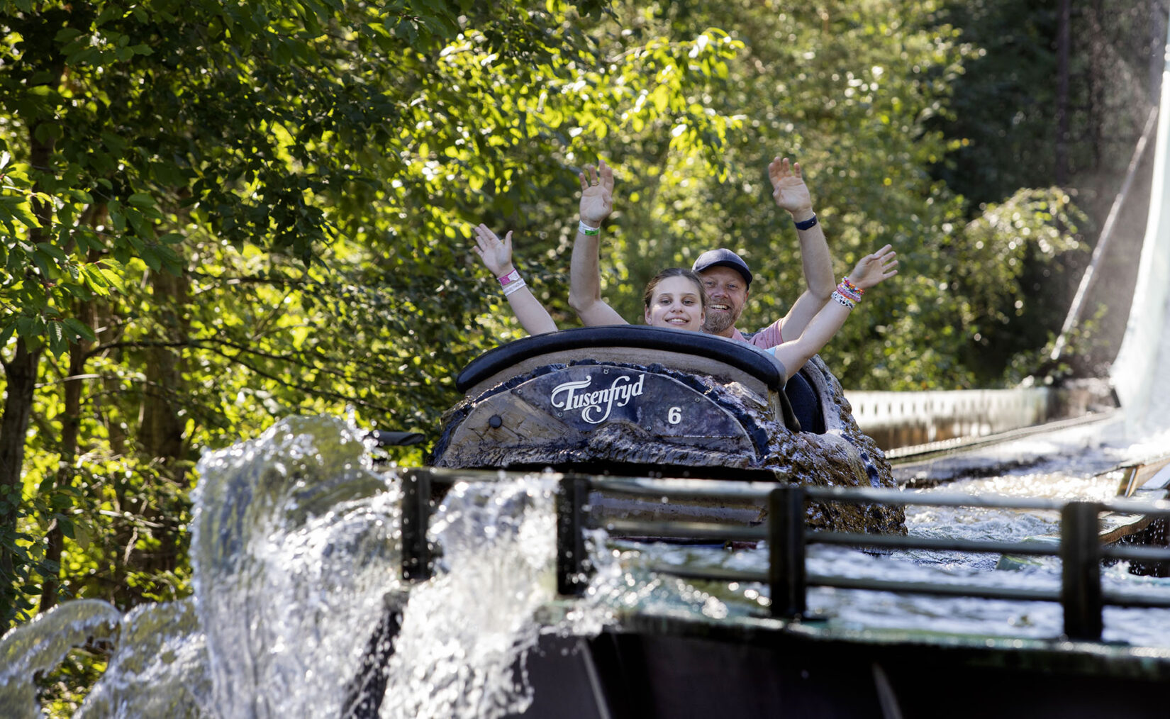 Jente i tømmerrenna i Tusenfryd sammen med pappa, begge har armene i været
