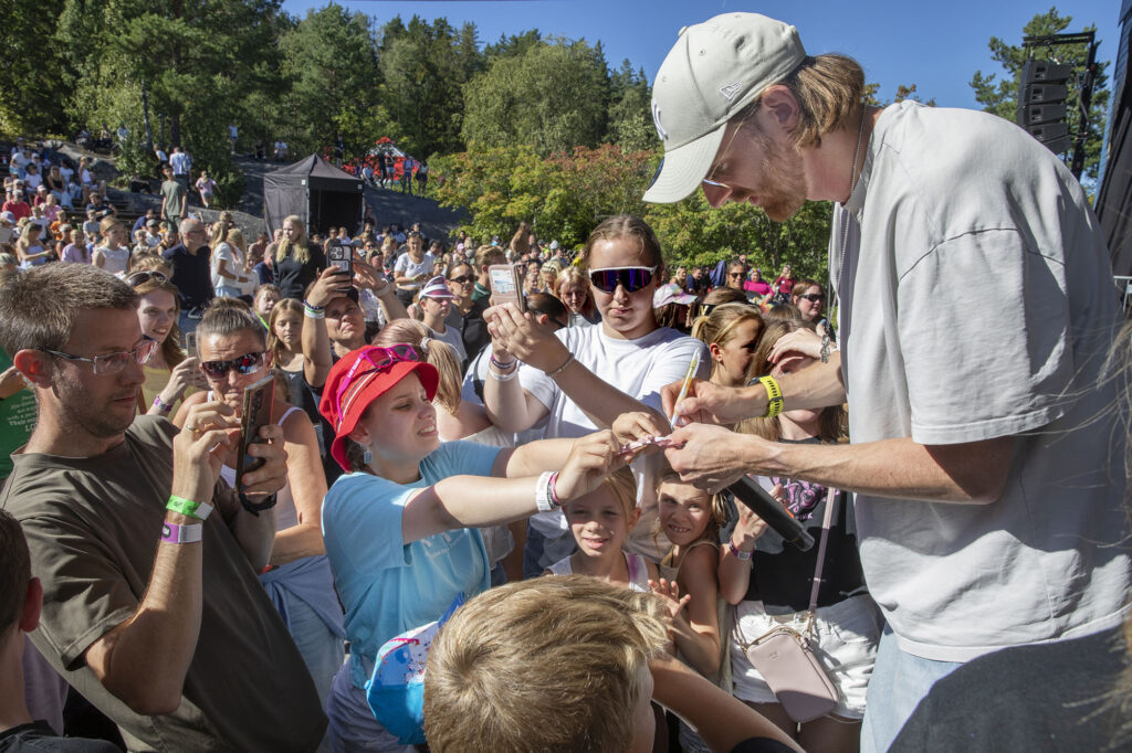 Tix skriver autotgraf til en jente midt i en stor folkemengde