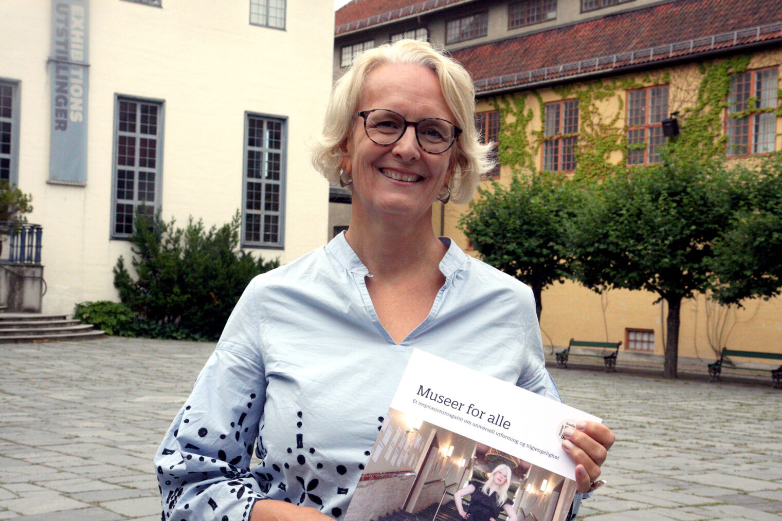 Marianne Alfsen viser frem nytt magasin foran Folkemuseets bygninger