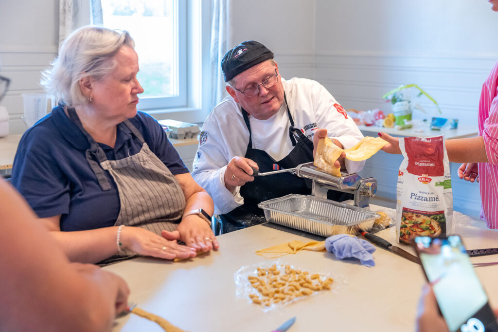 Tom Atle Steffensen viser Ann Karin Pettersen hvordan han bruker pastamaskinen