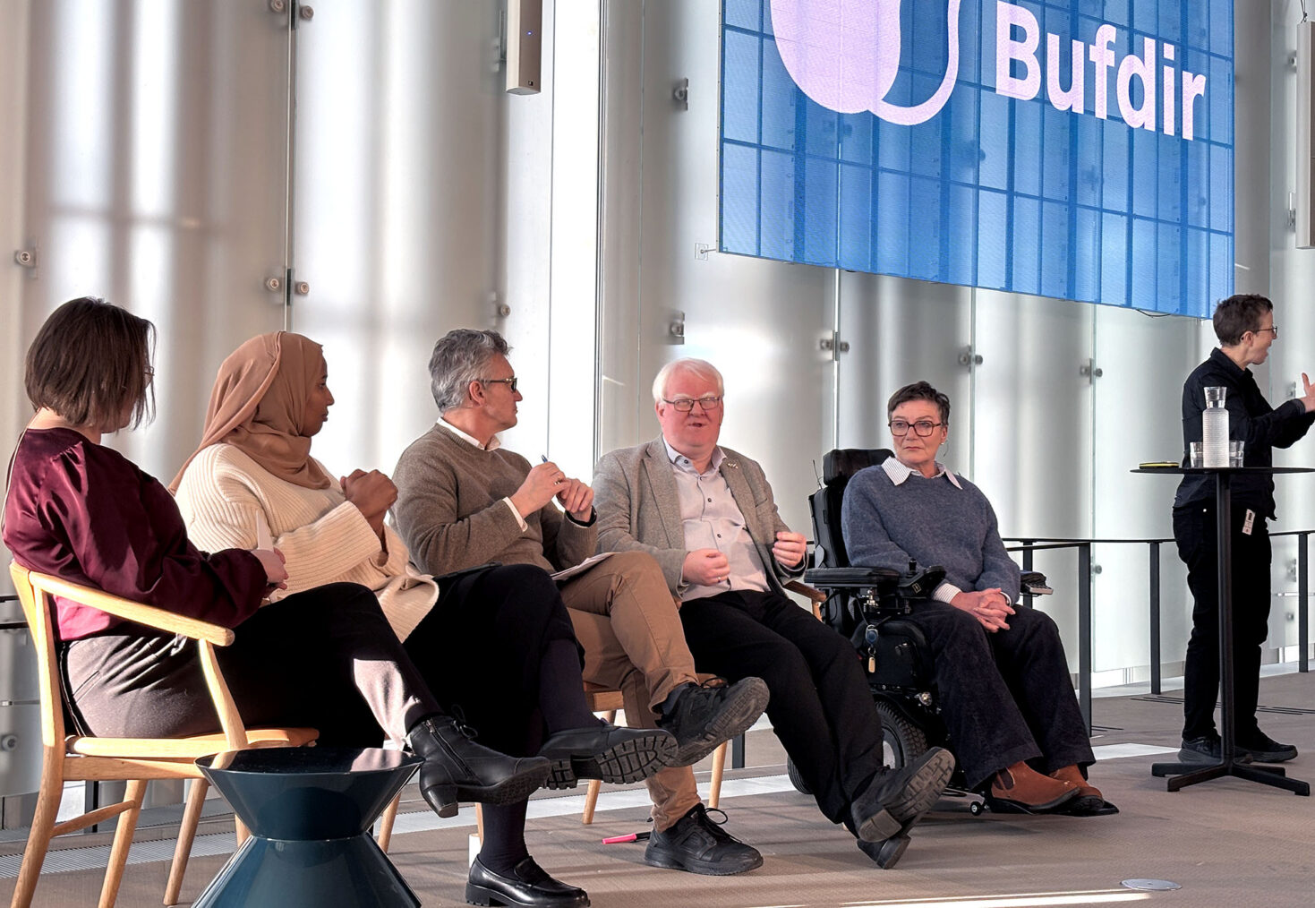 Tre kvinner og to menn i debattpanel. Tegnspråktolk i bakgrunnen.