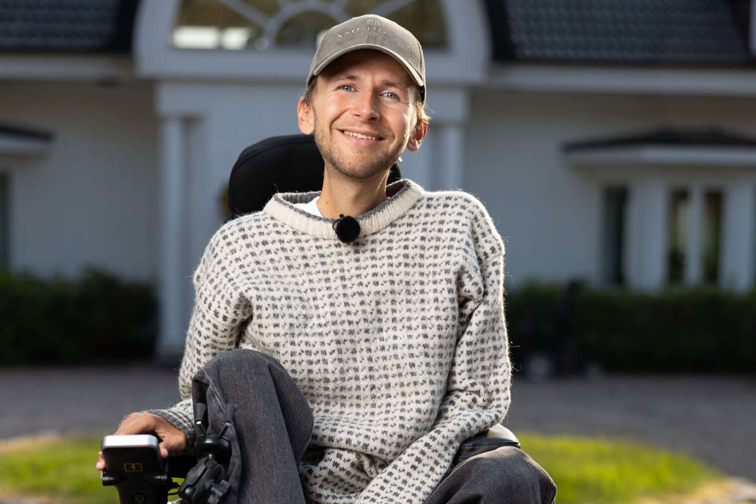 Daniel Maudal i elektrisk rullestol foran hvitt hus