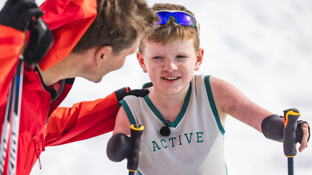 Benjamin Midtbø Høydal støtter seg på skistavene og lytter til instrukser fra Øystein Pettersen