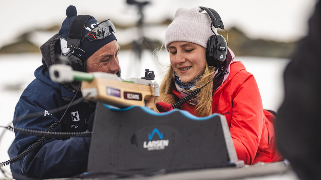 Jente på liggende standplass på skiskyting får hjelp av instruktør