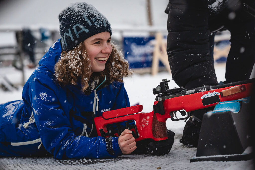 Synne Lykkeslet ligger med gevær på standplass i skiskyting