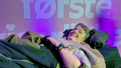 Marianne Knudsen foran fotovegg for Min første kjærlighet