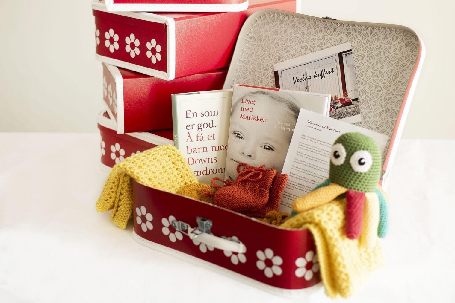 Rød barnekoffert med klær, kosedyr og informasjon