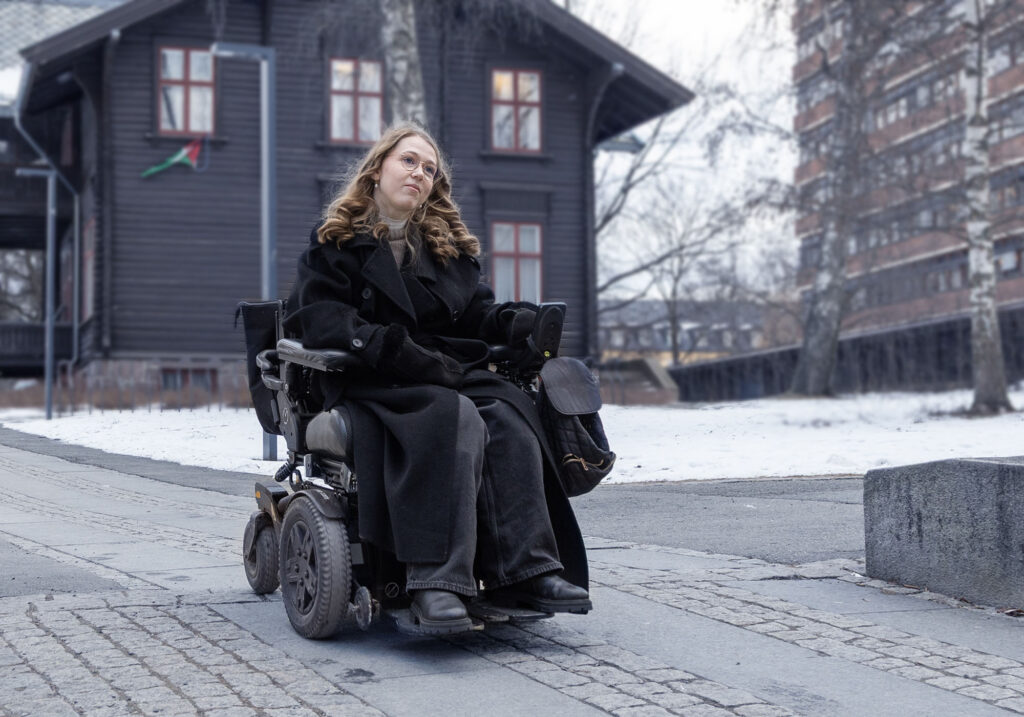 Marie Flaatten i el-rullestol på fortau på Blindern