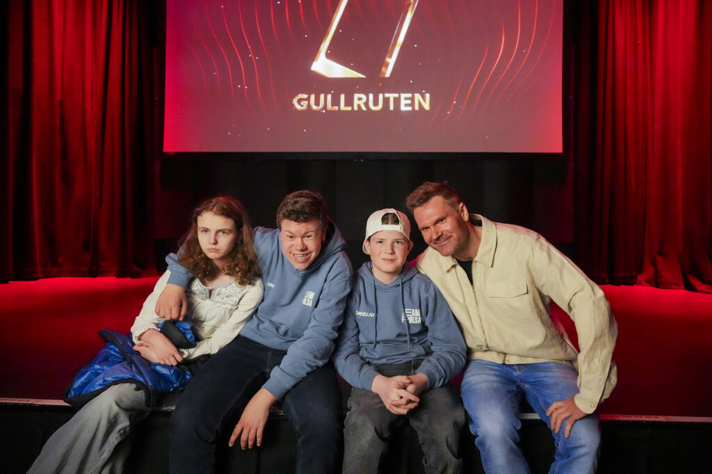 Synne Lykkeslet, Erik Tomter og Kornelius Smeby Ryen sammen med Øystein Pettersen i rød sofa foran logoen til Gullruten