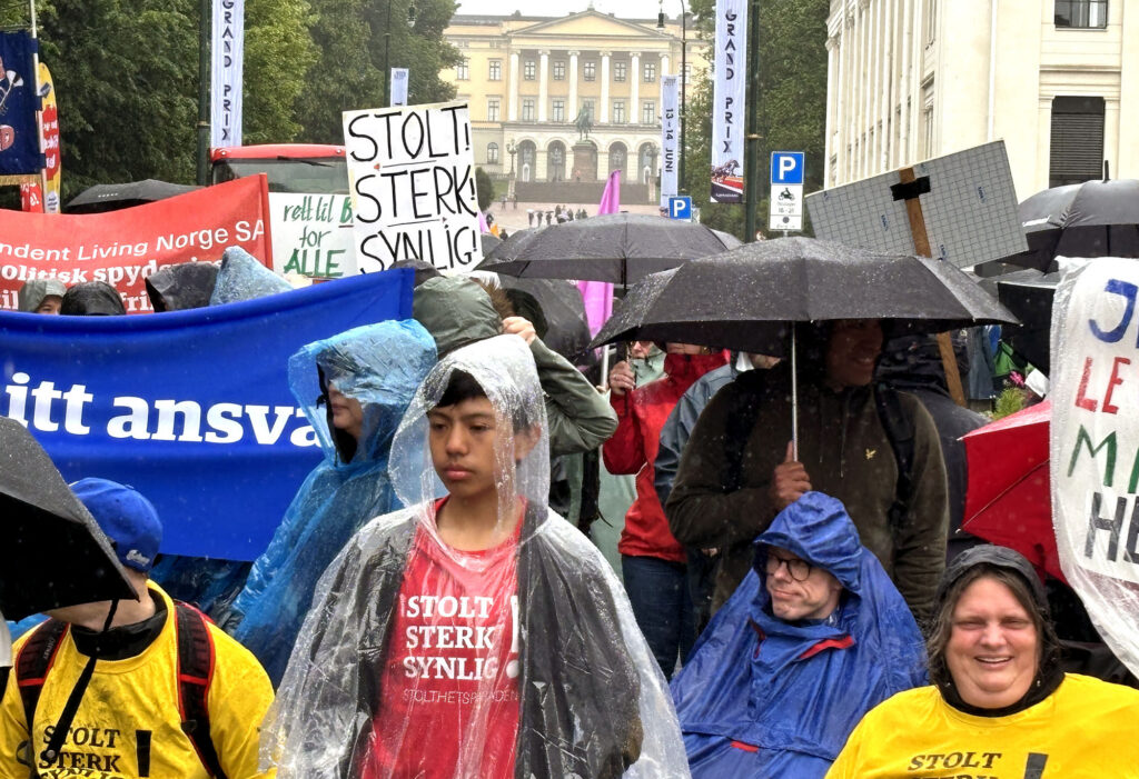 Stolthetsparadens deltakere med paraplyer, regnponchoer og annet regntøy på Karl Johan