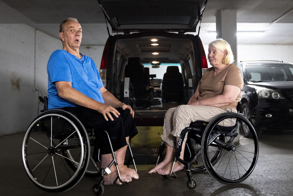 Erik Lillebye og Bente Bråthen i hver sin rullestol bak bilen i parkeringshus